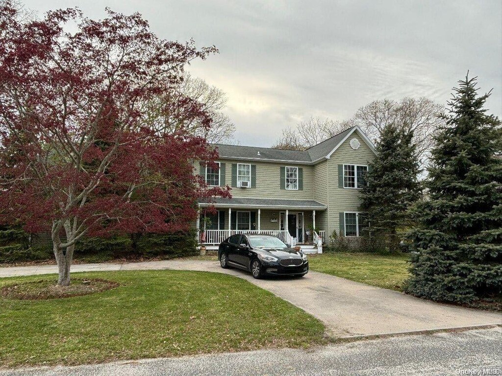 10 Coolidge Rd, Hampton Bays, NY 11946 - view of front facade featuring covered porch, driveway, and a front lawn