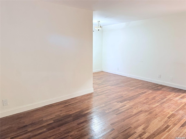 empty room featuring hardwood / wood-style floors and a chandelier