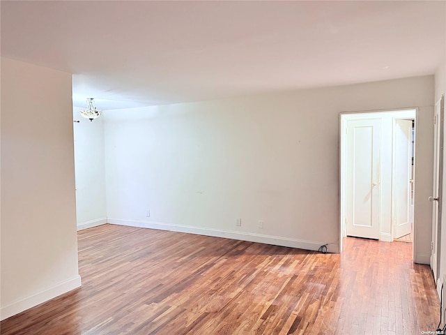 empty room with light hardwood / wood-style flooring and a notable chandelier