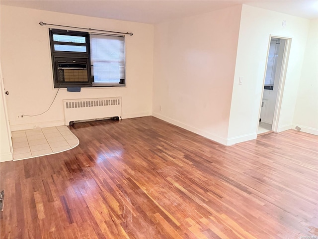 empty room with radiator, cooling unit, and hardwood / wood-style flooring