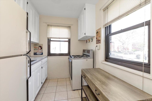 kitchen with white cabinets, light tile patterned floors, and white appliances