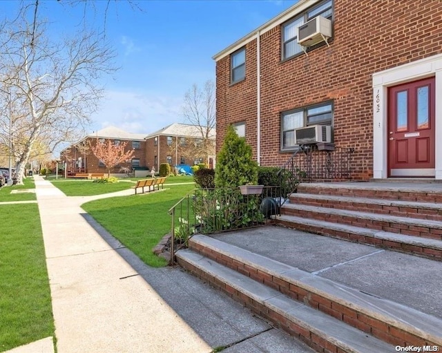 property entrance featuring cooling unit, a yard, and a wall unit AC