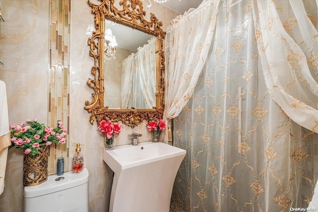 bathroom featuring sink, tile walls, and toilet