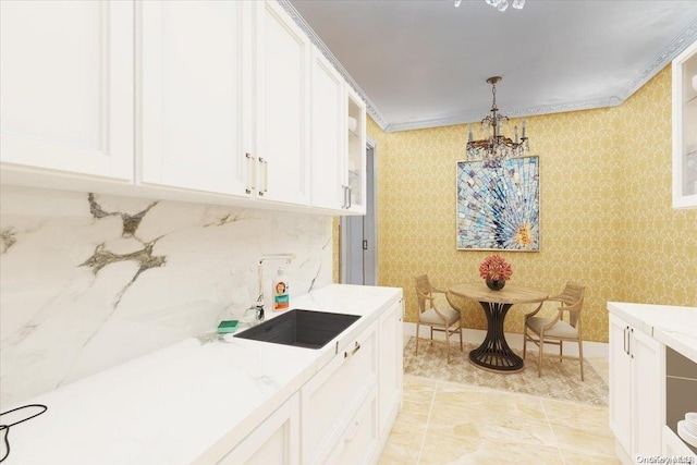 kitchen featuring sink, white cabinetry, and crown molding