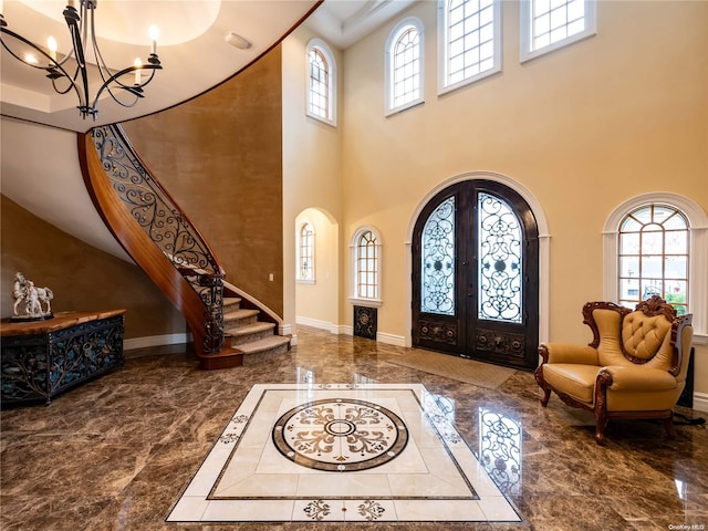 foyer entrance featuring french doors, a high ceiling, and an inviting chandelier