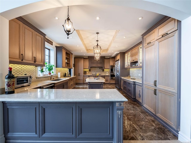 kitchen featuring backsplash, sink, hanging light fixtures, a tray ceiling, and kitchen peninsula