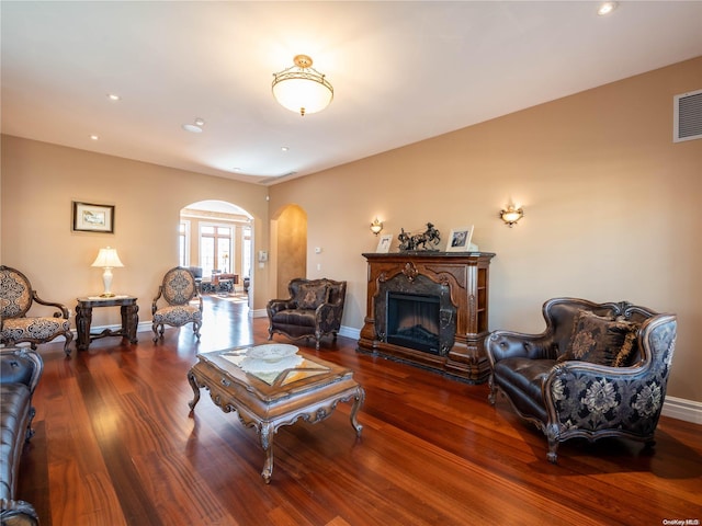 living room with a premium fireplace and dark wood-type flooring