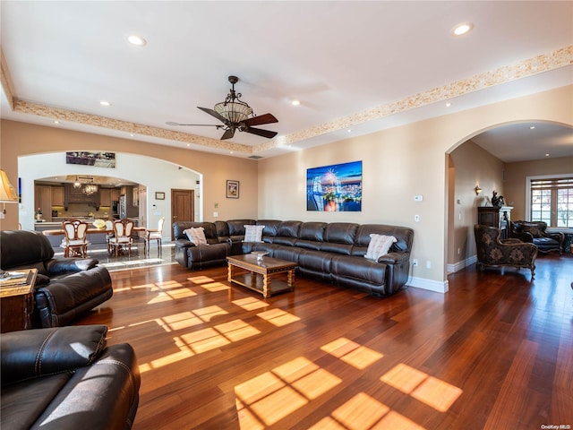 living room featuring hardwood / wood-style flooring, ceiling fan, and a raised ceiling