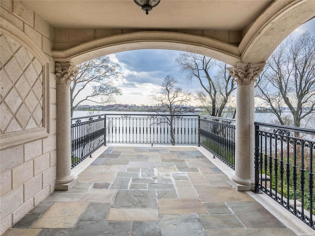 view of patio featuring a water view and a balcony