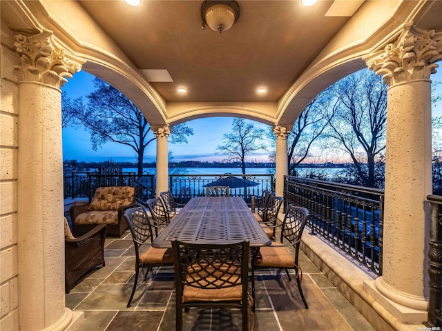 patio terrace at dusk with a water view and an outdoor hangout area