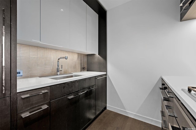 kitchen featuring decorative backsplash, dark hardwood / wood-style floors, white cabinetry, and sink