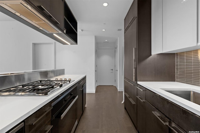 kitchen featuring backsplash, white cabinets, dark hardwood / wood-style floors, oven, and stainless steel gas stovetop