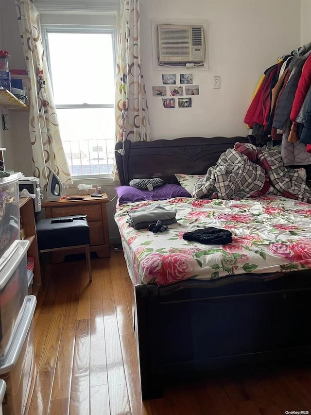 bedroom featuring a wall mounted air conditioner and hardwood / wood-style flooring