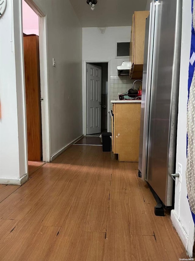 kitchen featuring stainless steel fridge, tasteful backsplash, ventilation hood, and hardwood / wood-style floors