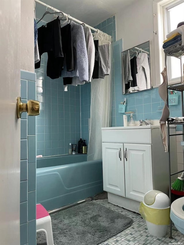 bathroom with tile patterned flooring, vanity, tile walls, and shower / tub combo