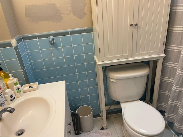 bathroom with toilet, tile patterned flooring, tile walls, and sink