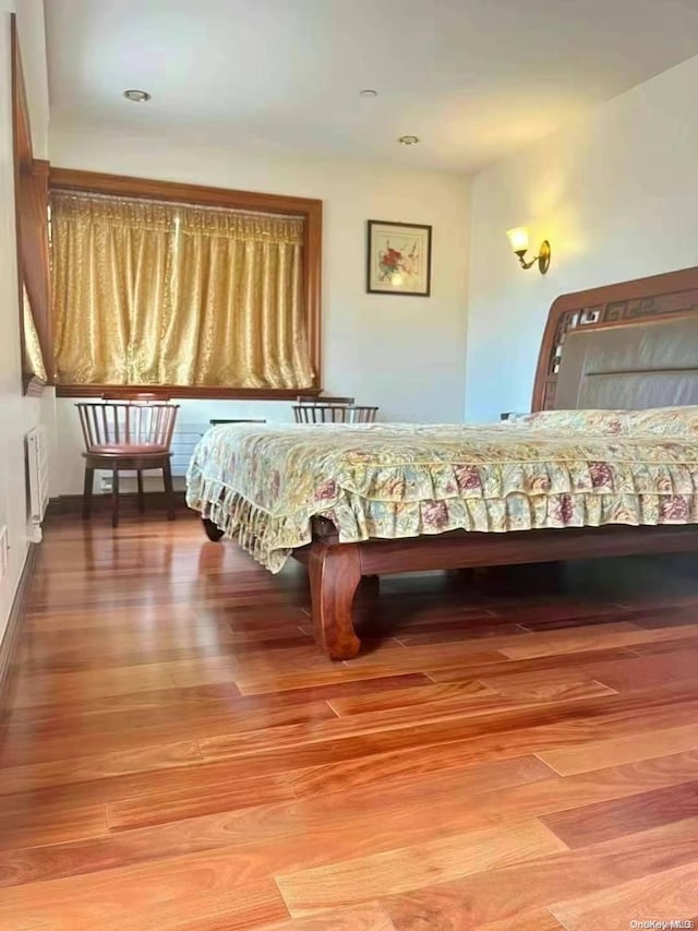 unfurnished bedroom featuring radiator and hardwood / wood-style floors