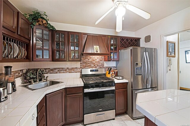 kitchen featuring custom range hood, stainless steel appliances, tile counters, and sink