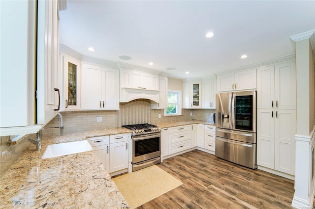 kitchen featuring light stone countertops, stainless steel appliances, sink, white cabinets, and hardwood / wood-style floors