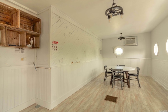 dining space with a wall mounted air conditioner, light wood-type flooring, and wood walls