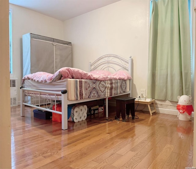 bedroom with wood-type flooring and radiator heating unit