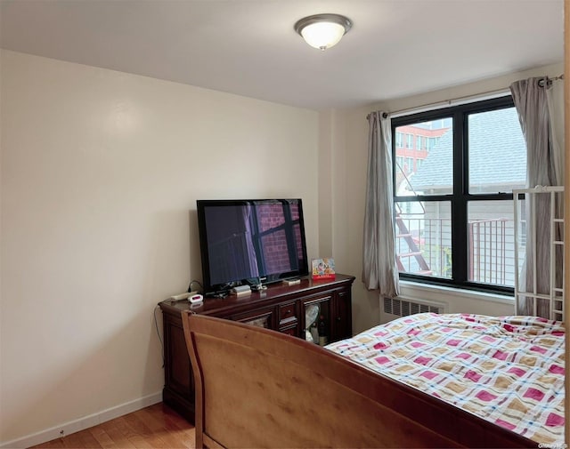 bedroom with light hardwood / wood-style floors and radiator