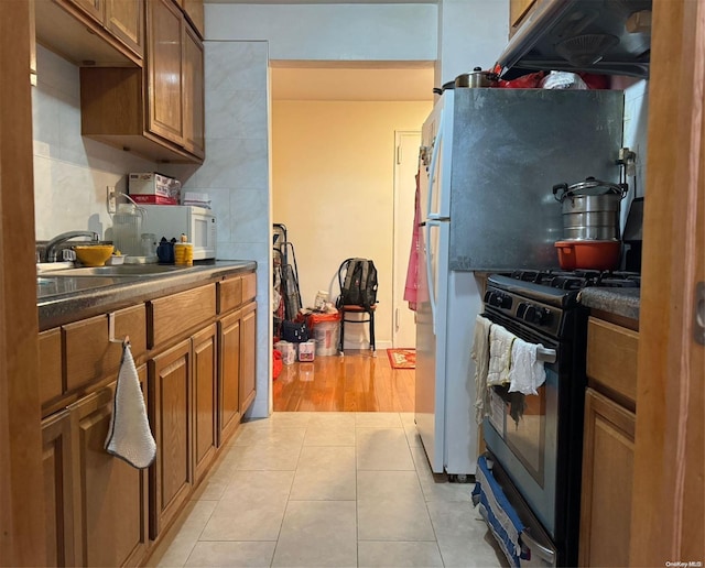 kitchen with black gas stove, sink, and light hardwood / wood-style flooring