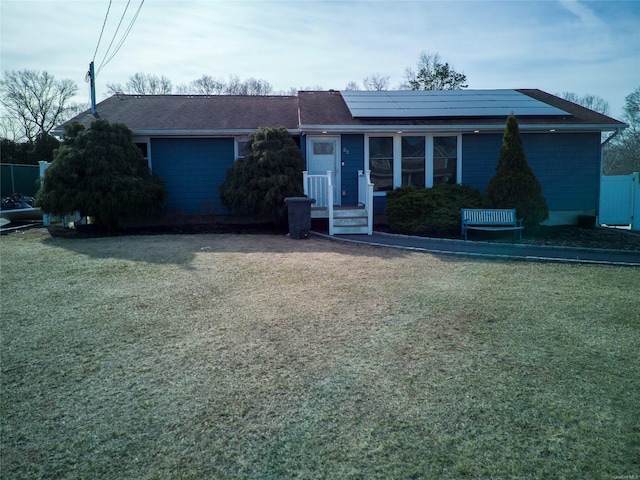 ranch-style house featuring a front lawn and roof mounted solar panels