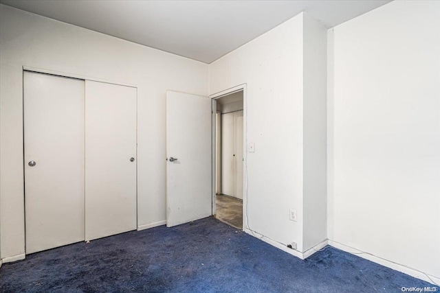 unfurnished bedroom featuring a closet and dark carpet