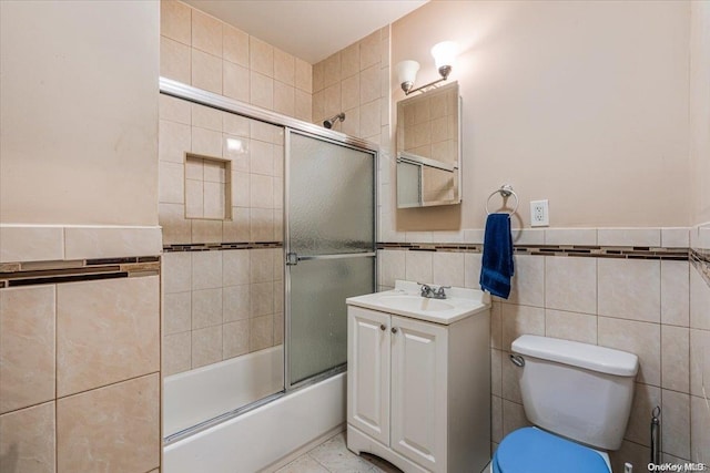 full bathroom with tile patterned flooring, toilet, shower / bath combination with glass door, vanity, and tile walls