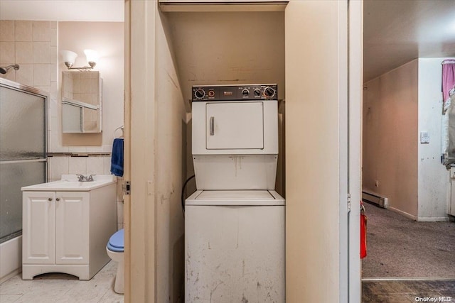 laundry area with sink, baseboard heating, and stacked washer and dryer