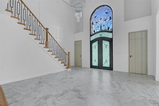 entrance foyer featuring french doors, a chandelier, and a high ceiling