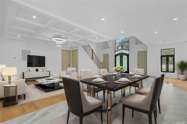 dining space featuring beamed ceiling, light hardwood / wood-style floors, an inviting chandelier, and coffered ceiling