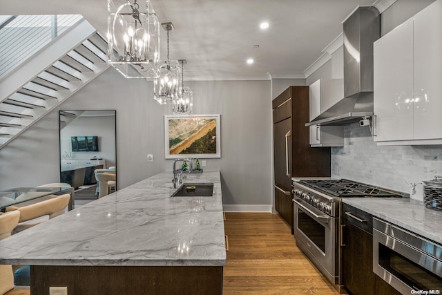 kitchen featuring white cabinetry, wall chimney range hood, sink, and appliances with stainless steel finishes