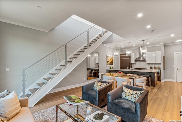 living room with an inviting chandelier, light hardwood / wood-style flooring, and crown molding