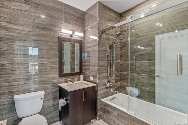 full bathroom with vanity, toilet, tiled shower / bath, and tile walls