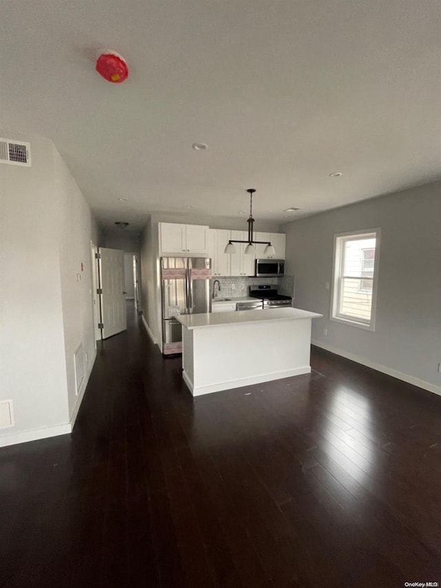 kitchen with appliances with stainless steel finishes, dark hardwood / wood-style flooring, pendant lighting, white cabinets, and a kitchen island