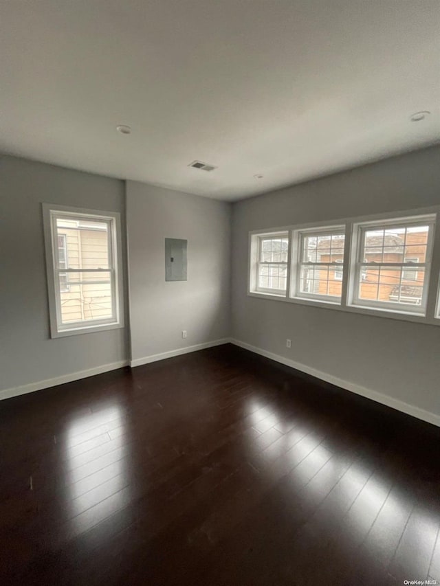 spare room with electric panel and dark hardwood / wood-style flooring