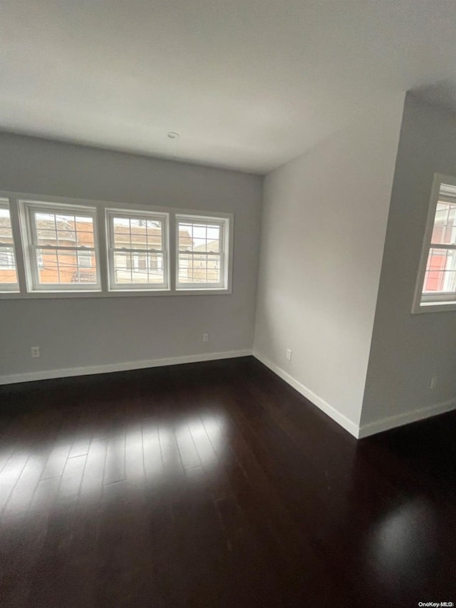 unfurnished room with plenty of natural light and dark hardwood / wood-style floors