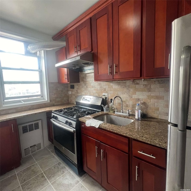 kitchen featuring dark stone counters, sink, decorative backsplash, appliances with stainless steel finishes, and radiator heating unit