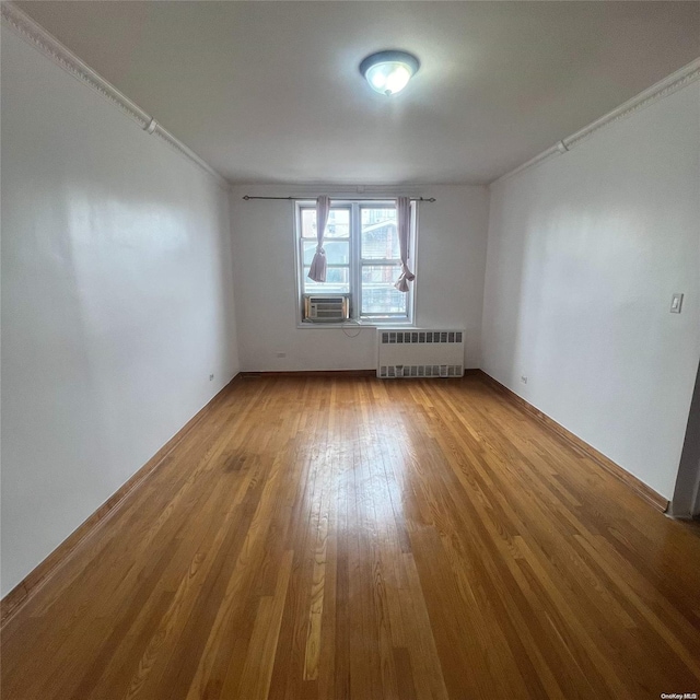 empty room featuring radiator, crown molding, cooling unit, and wood-type flooring