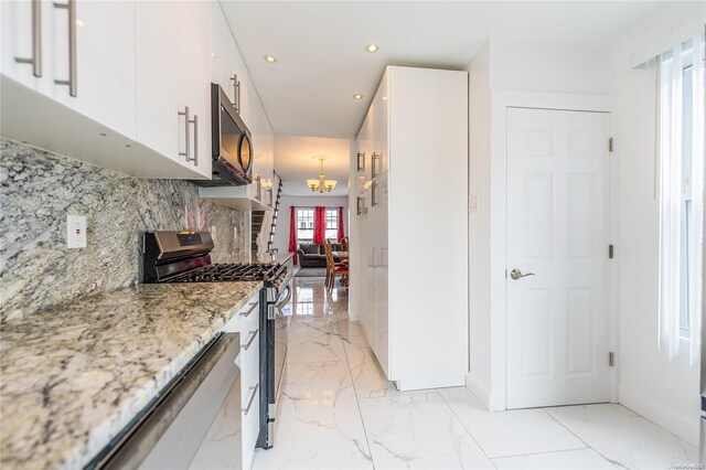 kitchen with white cabinets, a healthy amount of sunlight, light stone countertops, and appliances with stainless steel finishes