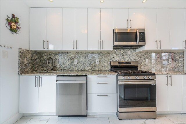 kitchen featuring white cabinets, stone counters, appliances with stainless steel finishes, and tasteful backsplash