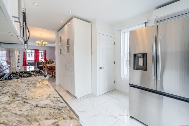 kitchen featuring white cabinets, a wall mounted air conditioner, light stone counters, and stainless steel fridge with ice dispenser