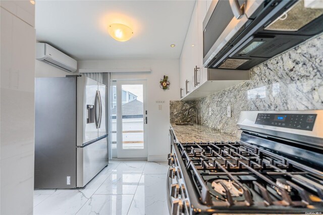 kitchen featuring a wall mounted AC, light stone countertops, white cabinets, and appliances with stainless steel finishes