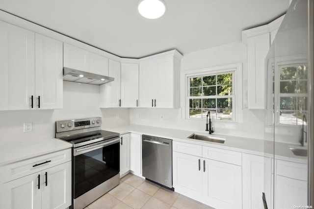 kitchen featuring ventilation hood, sink, light tile patterned floors, appliances with stainless steel finishes, and white cabinetry