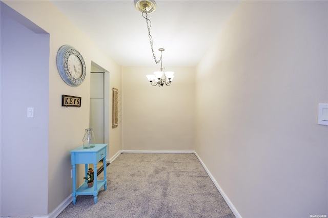 hall featuring light colored carpet and an inviting chandelier