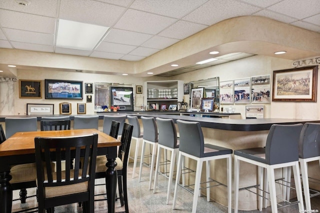 dining area featuring indoor bar, a paneled ceiling, and carpet floors