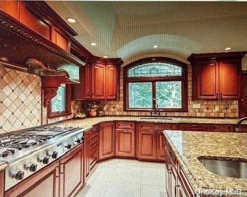 kitchen with a healthy amount of sunlight, light stone countertops, backsplash, and stainless steel gas cooktop