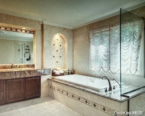 bathroom with vanity, ornamental molding, and tiled tub